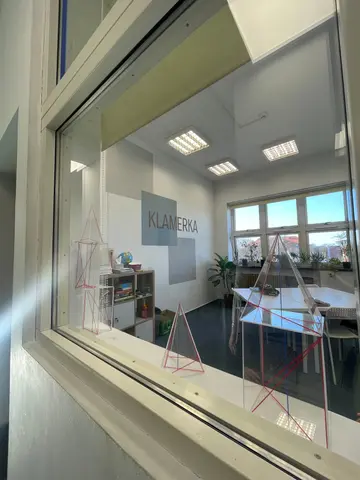 Sala zajęć Klamerki we Wrześni widziana przez wewnętrzne okno - logo i pomoce do geometrii